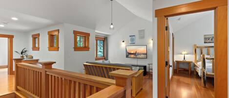 Une pièce spacieuse avec un escalier en bois, un coin salon avec un banc et un lit doté d’une tête de lit.