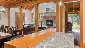 A spacious living area with a wooden ceiling, a stone fireplace, and a large dining table. - Suncadia Retreat • 3 porches • Quiet Cul-de-Sac • Fire pit • Bikes (Cle Elum)