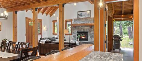 A spacious living area with a wooden ceiling, a stone fireplace, and a large dining table.