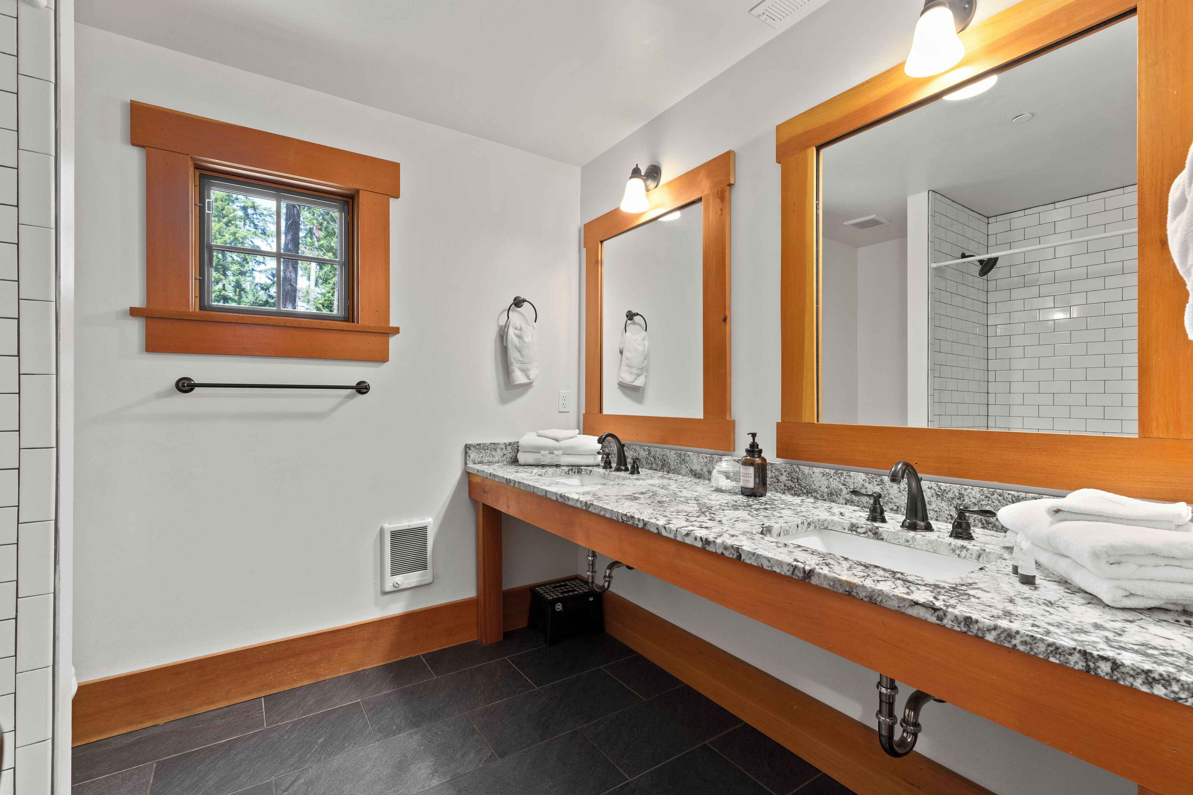 Un ba ño con un lavamanos amplio, dos lavabos, una ventana y un espejo grande.