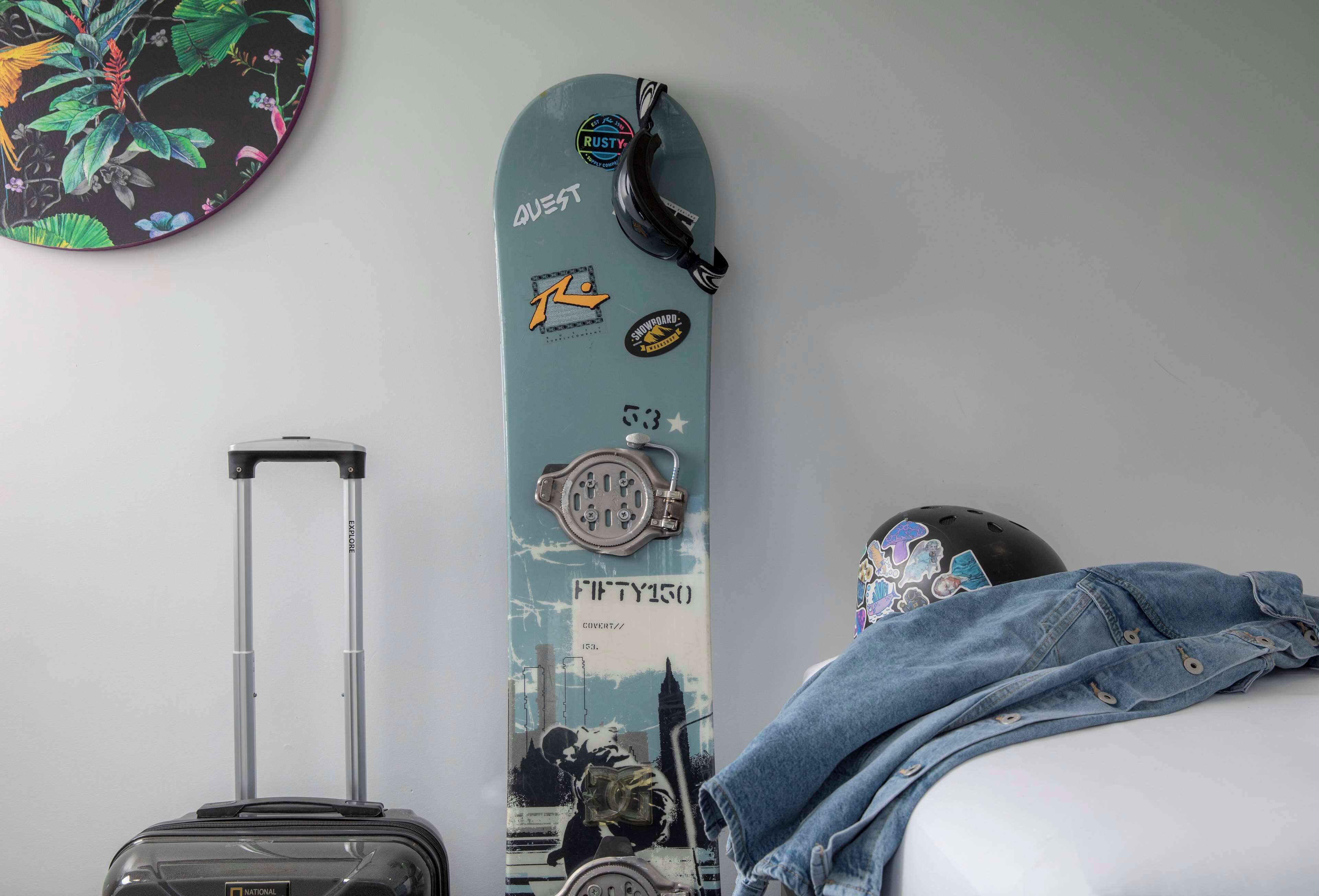 Quarto com um patinete, mala e capacete sobre a cama.