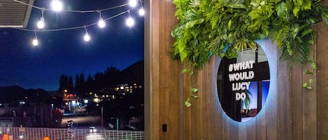 Een muur met een spiegel die een nachtzicht weerspiegelt, sfeerverlichting en een weelderige, groene plantencompositie.