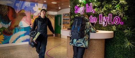 A reception area with a neon sign that reads "Say hi, to LyLo." and a wall decorated with plants.