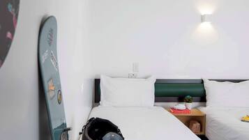 A hotel room with a bed, a nightstand, a surfboard, and a helmet.
