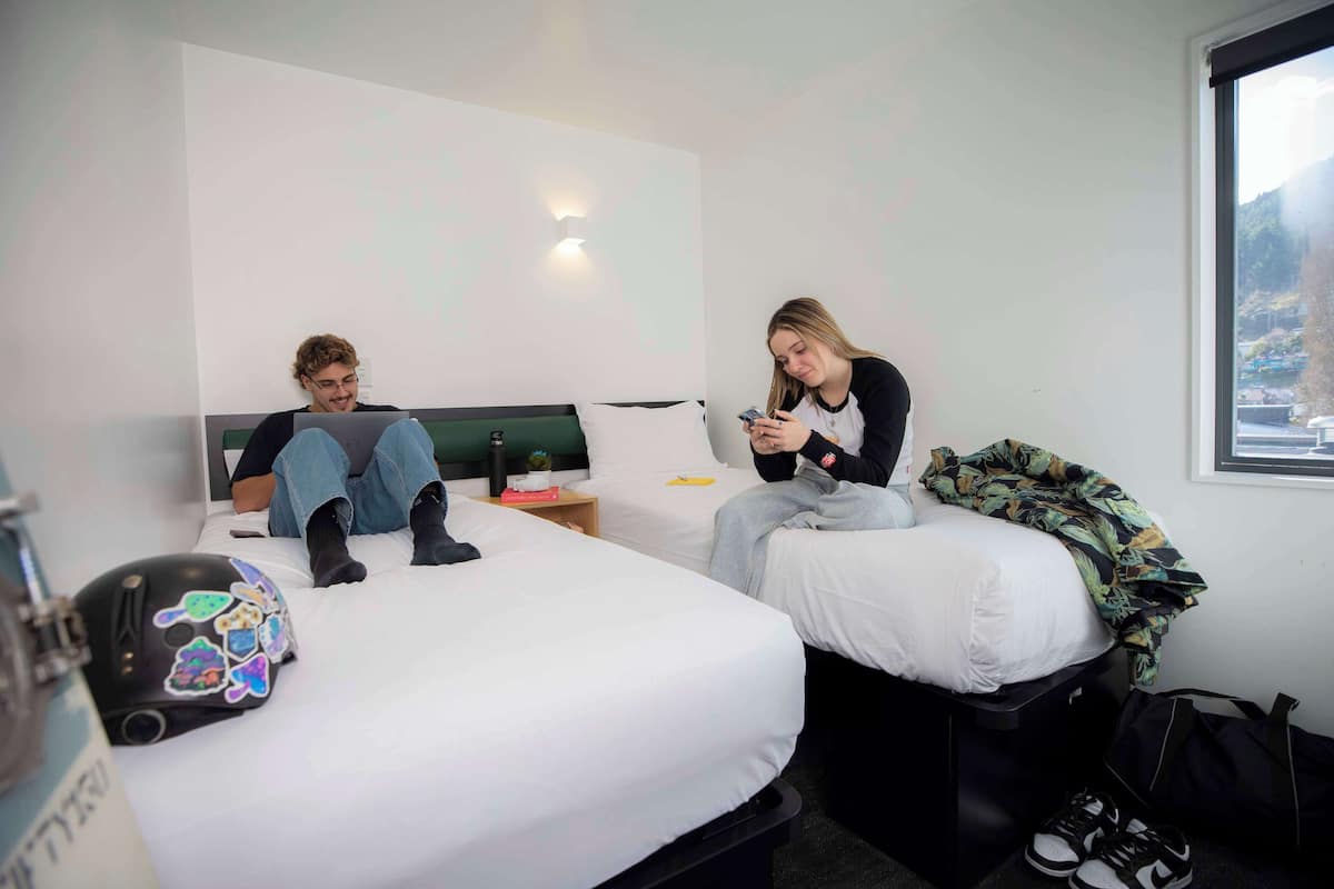 Ein Hotelzimmer mit zwei Betten, einem Nachttisch und einem Fenster mit Blick.