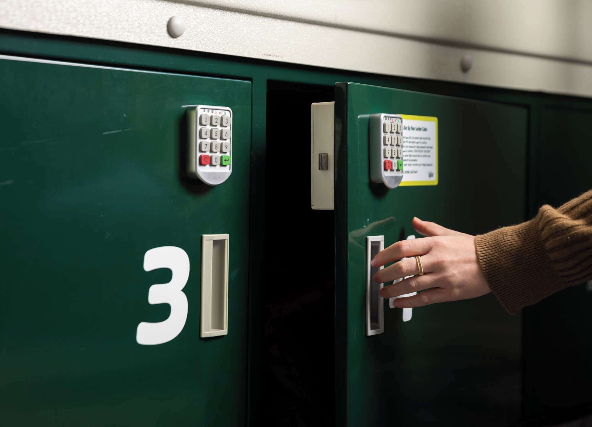 A hand operating a keypad lock on a green filing cabinet with the number 31 visible.