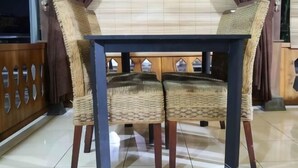 A dining area with a table and chairs, wooden paneling, and a view through a window. - Griya Limasan Gunung Kidul (Wonosari)