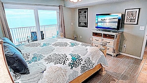 A bedroom with a large bed, a ceiling fan, a television, and a view of the ocean through the balcony doors. - Beachside Gulf front 3BR,2BA condo in Indian Shores, FL Spectacular Sunsets! (Indian Shores)