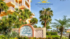 A sign for The Beach Cottage with a clear view of a multi-story building in the background. - Beachside Gulf front 3BR,2BA condo in Indian Shores, FL Spectacular Sunsets! (Indian Shores)