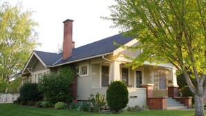 Una casa de un piso con porche delantero, chimenea y césped cuidado.