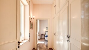 A hallway with a wooden floor, white walls, and a door leading to a bedroom.