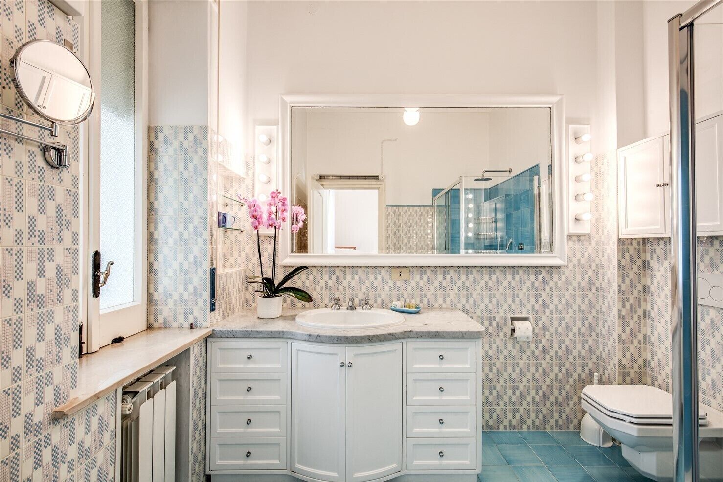 A bathroom with a vanity, a large mirror, and a toilet.