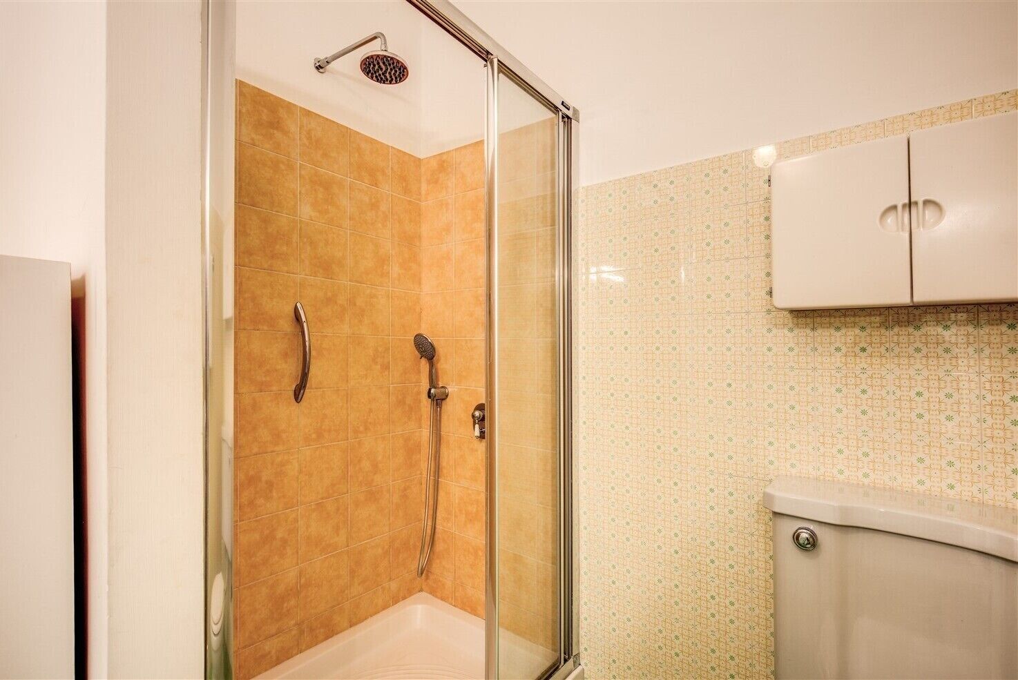Un bagno con doccia vetrata, un water e un armadietto.
