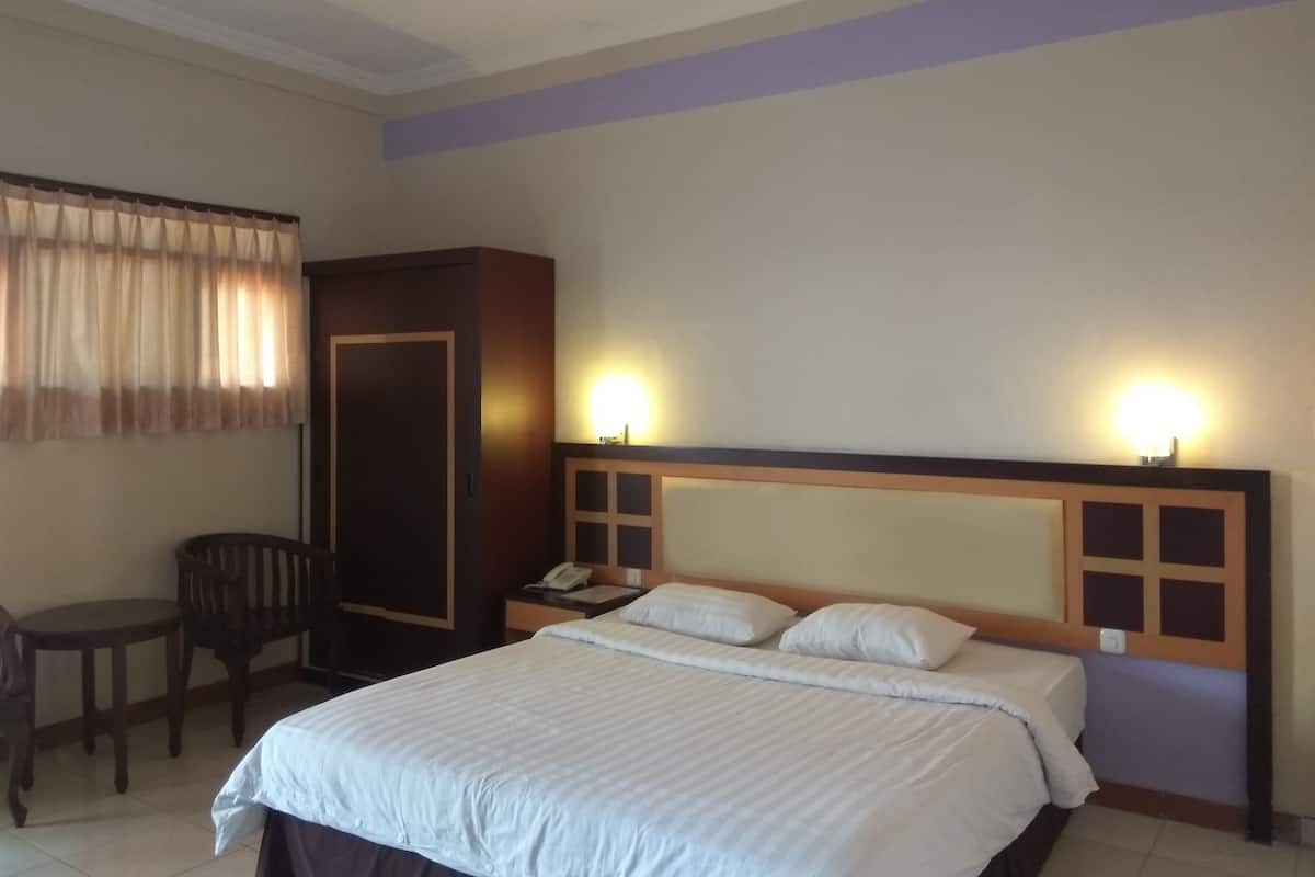 Hotellihuone, jossa on sänky, työpöytä ja vaatekaappi.