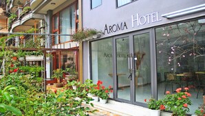 Un hotel con fachada moderna, puertas de vidrio grandes y un balcón con macetas y flores.