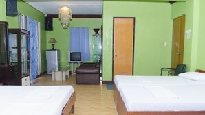 A hotel room with two beds, a television, a desk with a lamp, and a small seating area. - Little Falls Inn (Tagaytay)