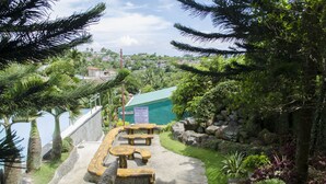 A view of a garden area with picnic tables and a sign indicating guidelines. - Little Falls Inn (Tagaytay)