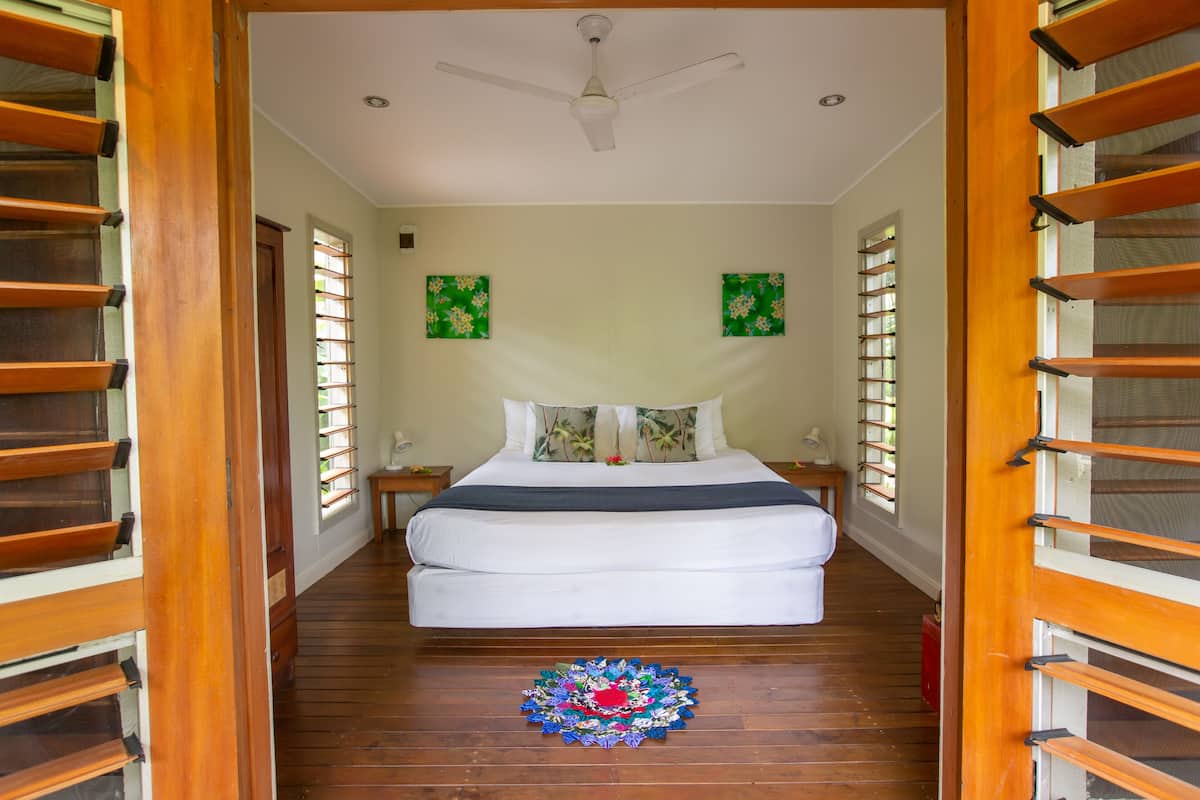 Quarto com uma cama, um ventilador de teto e duas pinturas nas paredes.