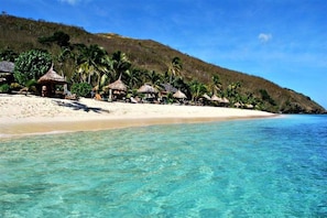 Praia particular, areia branca, espreguiçadeiras, guarda-sóis