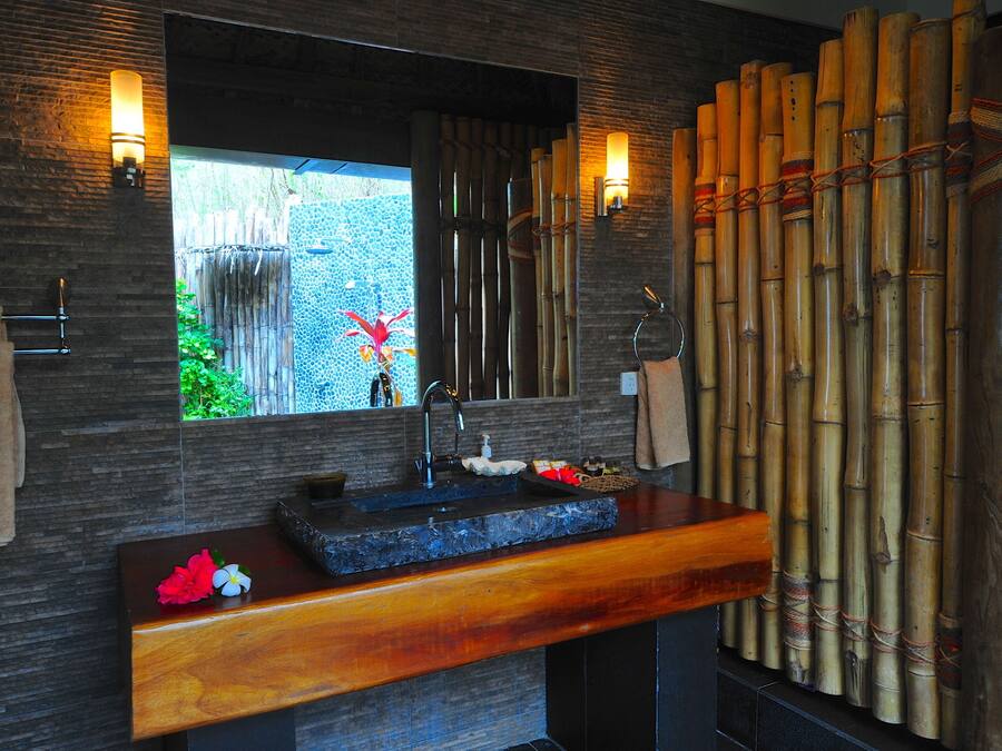 A bathroom with a stone sink, wooden vanity, and a window with a view of greenery.
