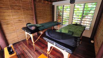 Relax in a serene space with two massage tables, a wooden stool, and a clock on the wall.