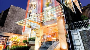 A multi-story hotel with a modern facade, illuminated signage, and a staircase leading to the entrance. - Best City Hotel (Yogyakarta)