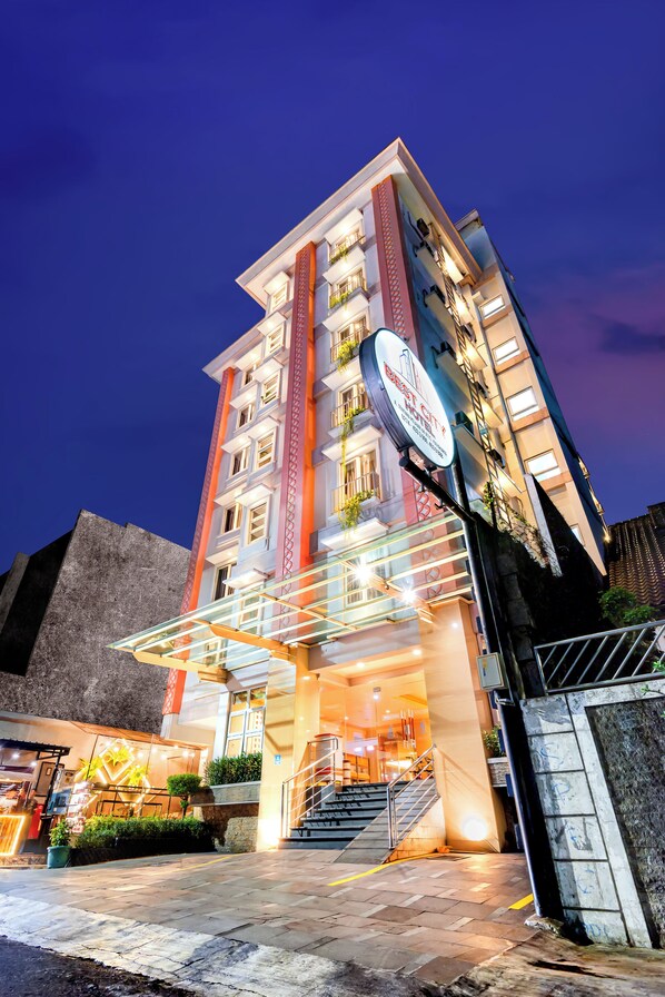 A multi-story hotel with a modern facade, illuminated signage, and a staircase leading to the entrance.
