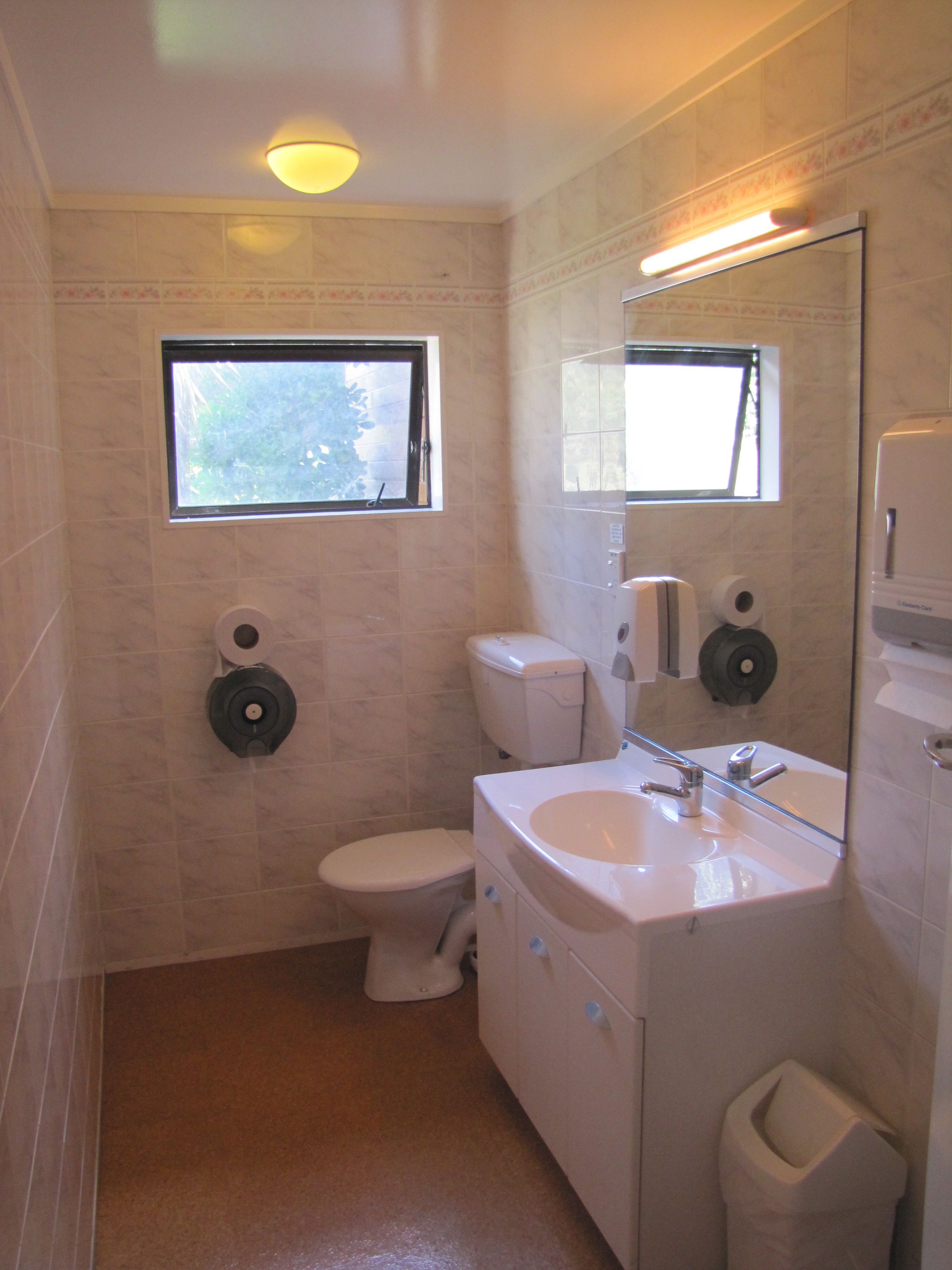A compact bathroom with a toilet, sink, and mirror.
