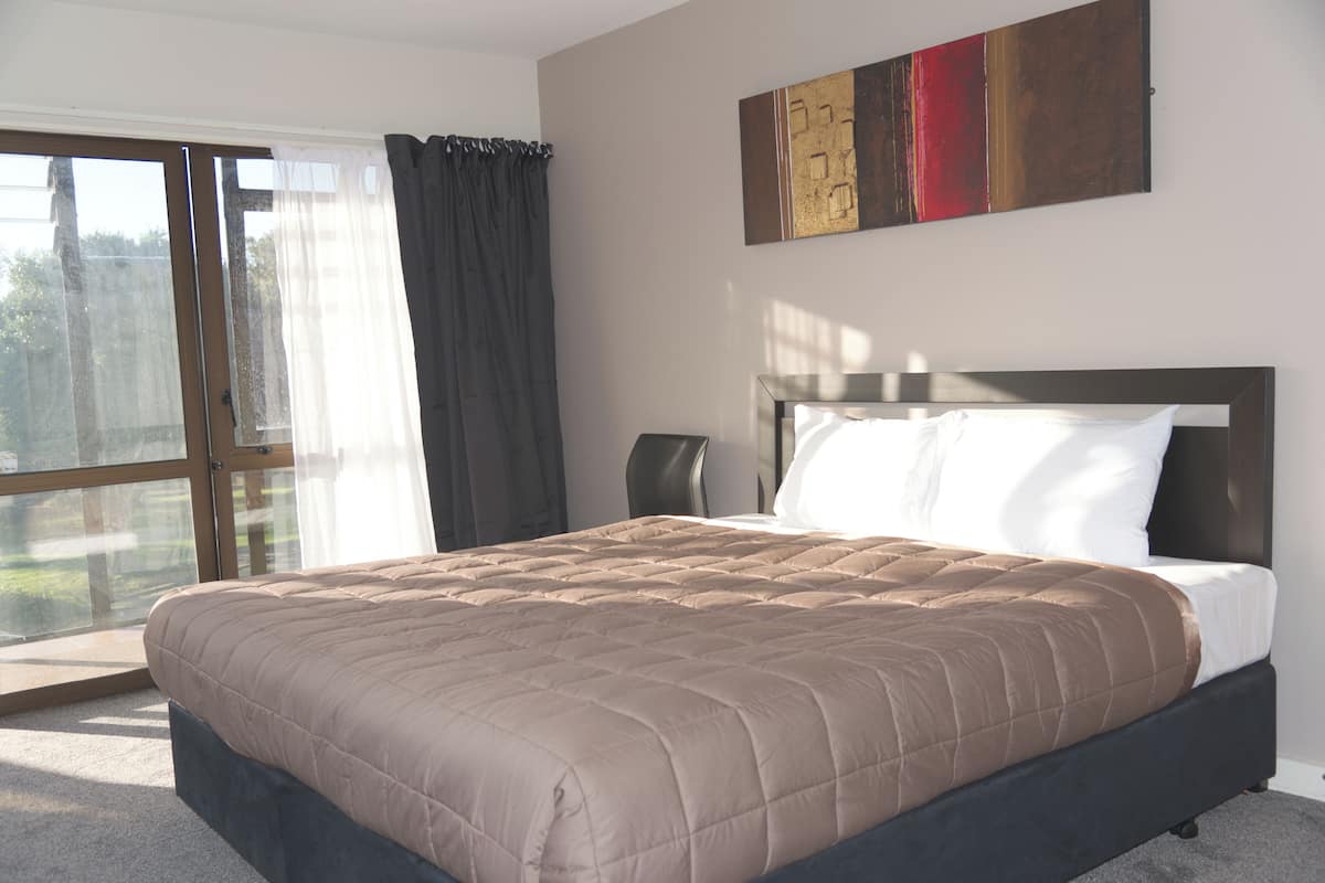 Un dormitorio con una cama grande, un ventanal corredero y vistas al exterior.