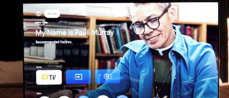 A television screen displaying a TV show intro with a person in a blue jacket.