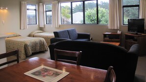 Una habitación con dos camas, un sofá, una mesa de comedor de madera y un televisor.