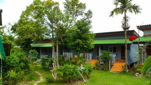 A traditional building with a green roof, surrounded by lush greenery and a clear path leading to the entrance. - Bonus Bungalow (Chalong)