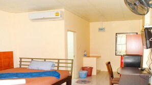 A bedroom with a bed, an air conditioner, a desk with a chair, and a television. - Bonus Bungalow (Chalong)