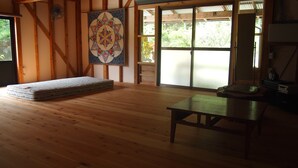 A room with wooden flooring, a bed, a table, and a large window with a view of greenery. - Rulo Classic Garden (Kaiyo)