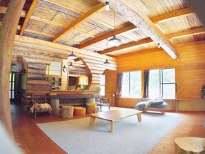 A log cabin interior with a wooden floor, a fireplace, a sofa, and a dining table. - Rulo Classic Garden (Kaiyo)