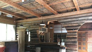 A rustic log cabin interior with a wooden ceiling, a large window, and a dining area. - Rulo Classic Garden (Kaiyo)