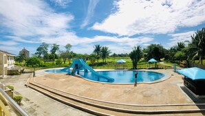 A swimming pool with a blue slide, surrounded by palm trees and a clear sky. - Queens Island Golf and Village (Medellin)