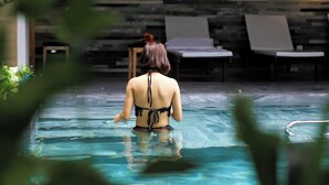 A person in a swimming pool with lounge chairs and a stone wall in the background. -  John Boutique Villa  (Da Nang)