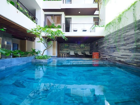 Una piscina al aire libre, sillones reclinables de piscina