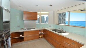 Una cocina moderna con horno empotrado, un lavabo y ventana con vista al mar.