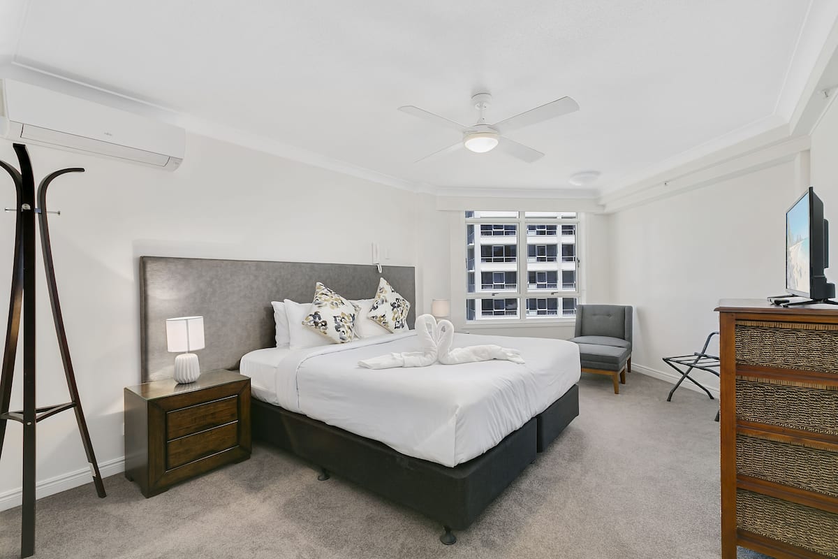 A bedroom with a bed, nightstand, lamp, and a chair.