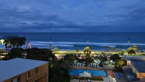 Un hotel frente a la playa con piscina, sillas de playa y una torre de salvavidas.