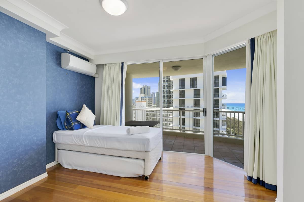 A bedroom with a bed, a window, and a view of buildings.