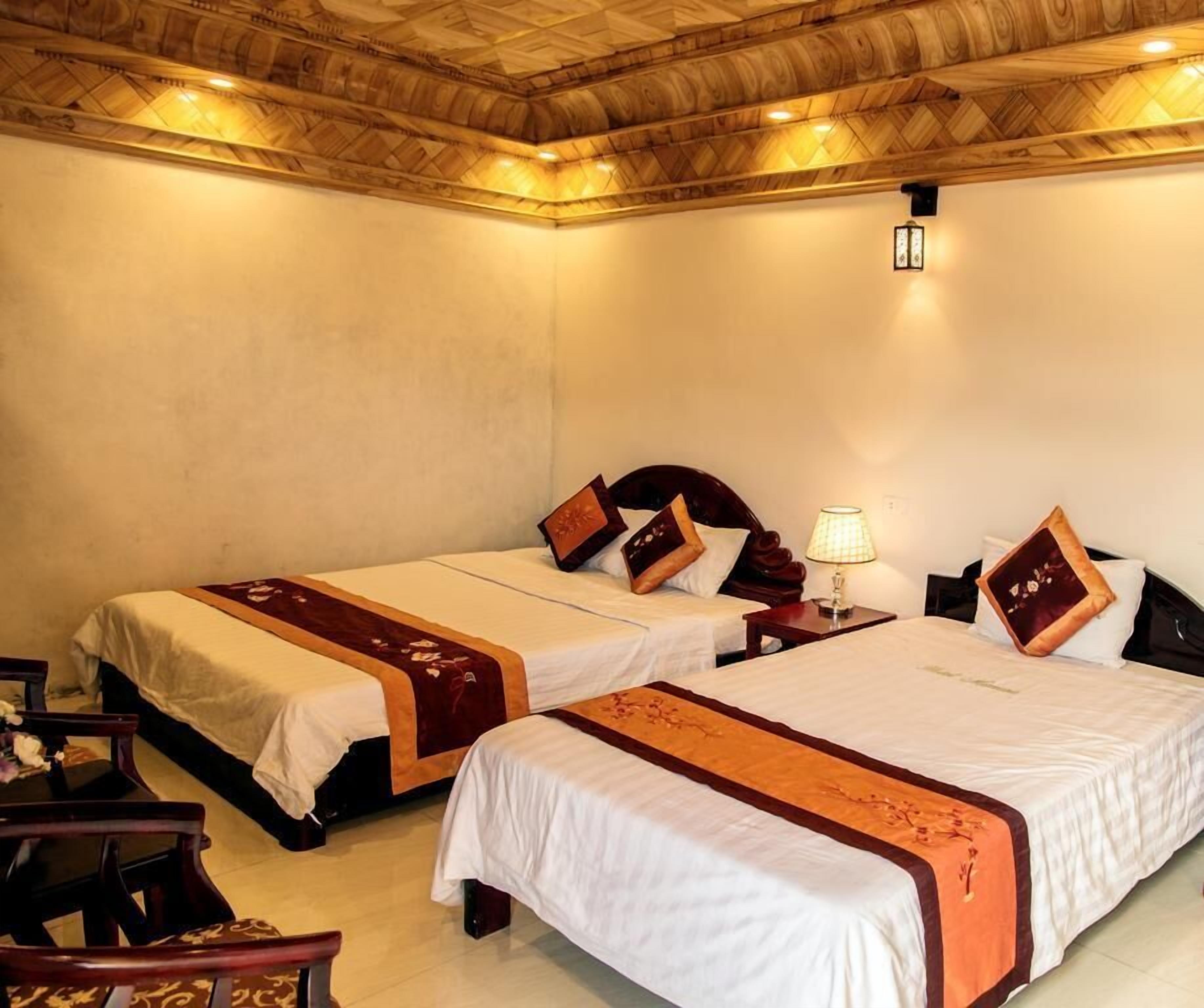 A hotel room with two beds, wooden headboards, and a ceiling with a geometric pattern.