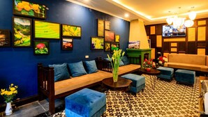 A modern lounge area with a sofa, ottomans, and a coffee table. - Sapa Mimosa Hotel (Sa Pa)
