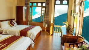 A hotel room with two beds, wooden floors, a balcony with a view of mountains, and a table with a vase of flowers. - Sapa Mimosa Hotel (Sa Pa)