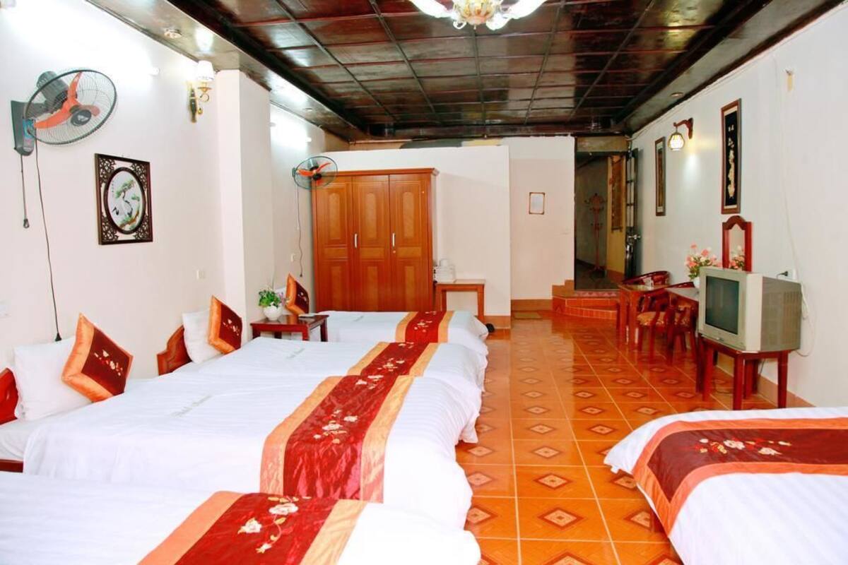 Habitación de hotel con dos camas, un armario de madera, televisión y suelo de baldosas.