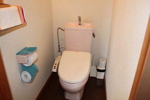 A small bathroom with a toilet, a toilet paper holder, and a bidet.