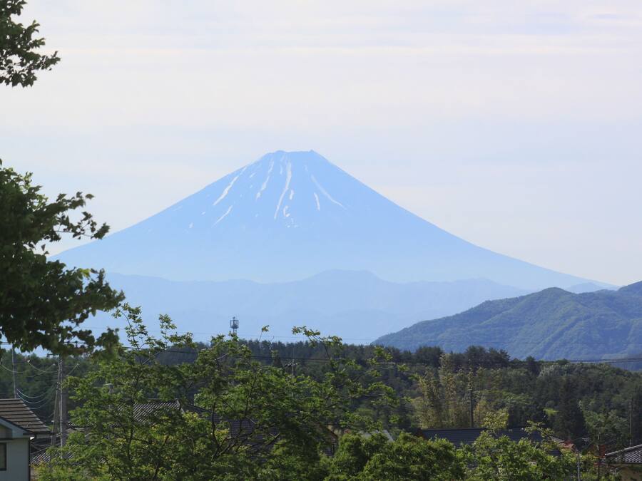 A mountain with a conical shape, surrounded by greenery and houses.