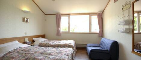A room with two beds, a sofa, a window with curtains, a mirror, and a wall-mounted towel rack.